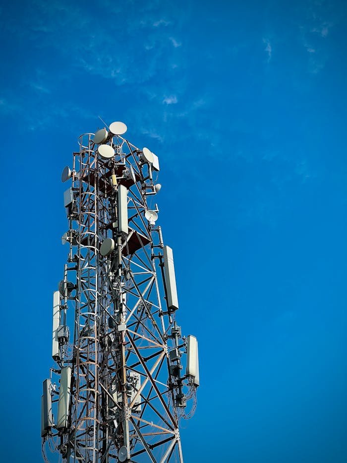 Close-up view of a telecommunication tower with antennas and dishes under a clear blue sky, showcasing modern infrastructure.